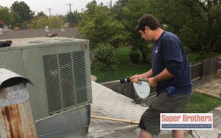 hvac technician cleaning ac condenser on the roof