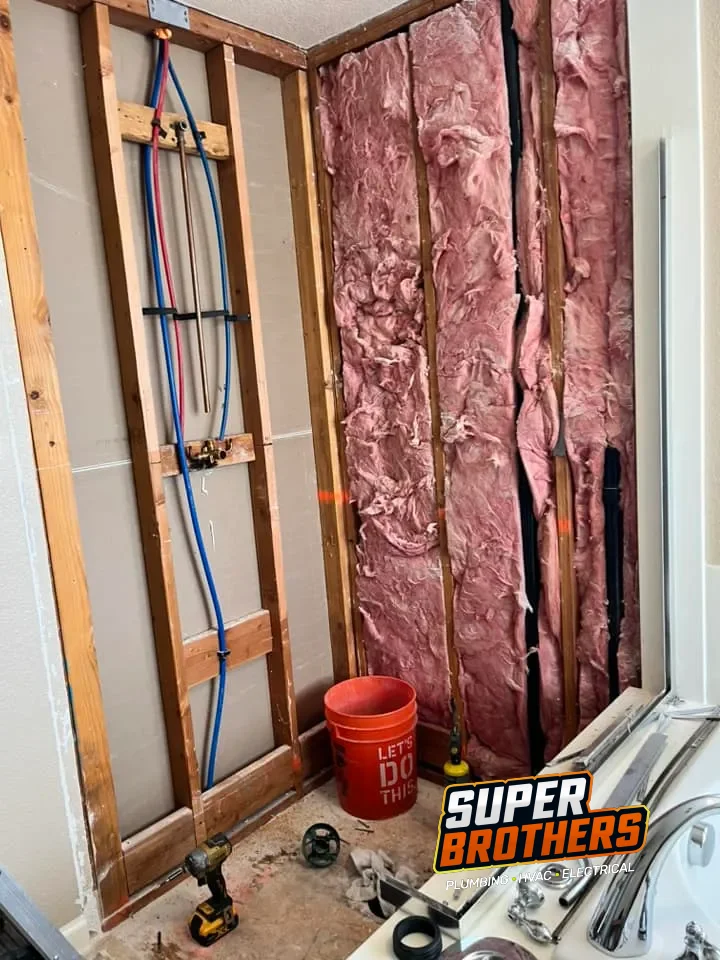 Licensed plumber routing flexible PEX water lines through residential framing