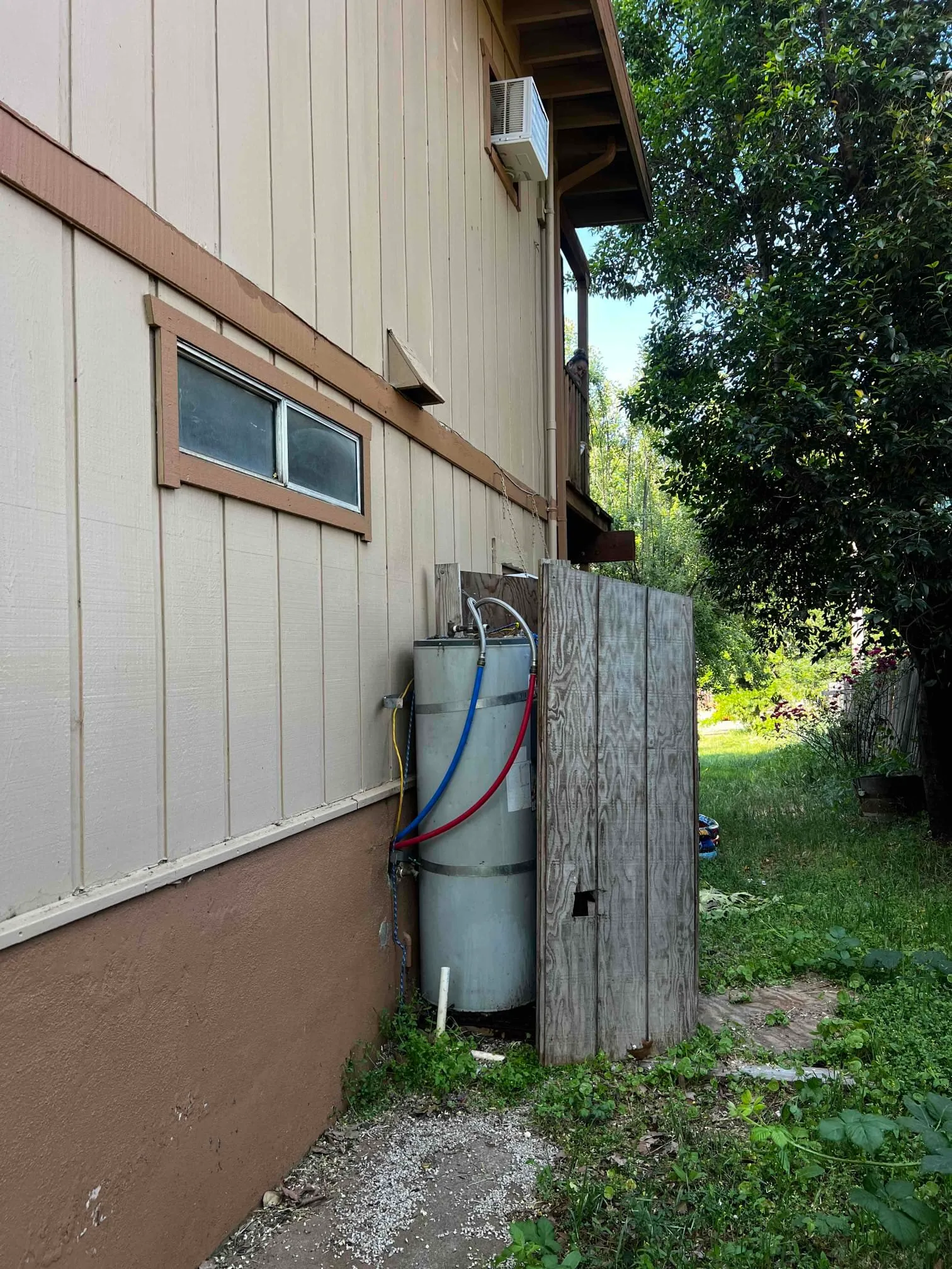 Plumber inspecting corrosion and leak signs on an older water heater