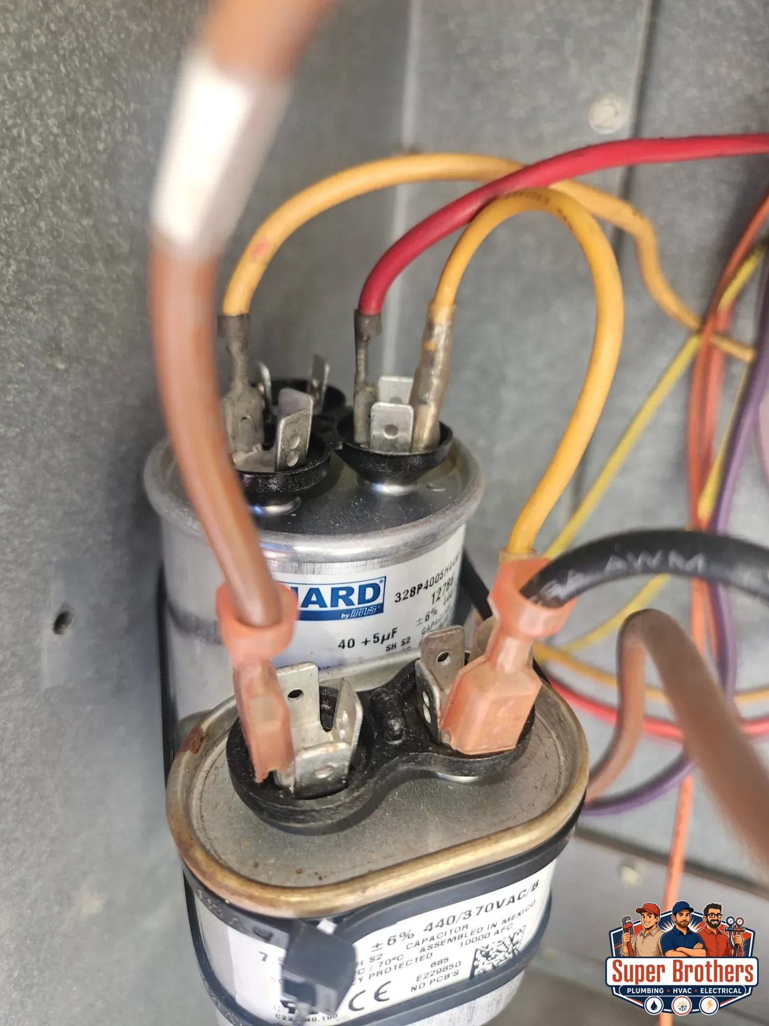 two capacitors and wiring inside rooftop packaged AC electrical cabinet