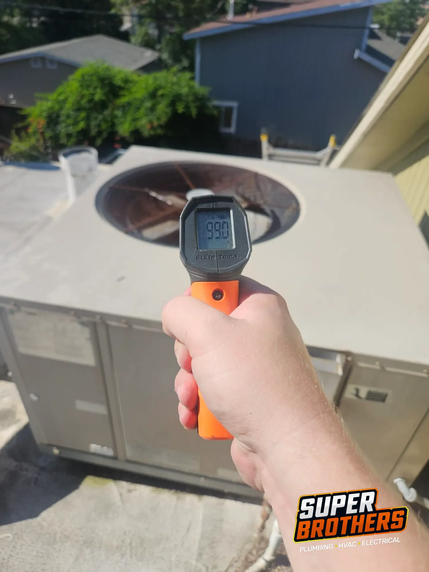 technician checking rooftop AC surface temperature near condenser fan technician checking rooftop AC surface temperature near condenser fan