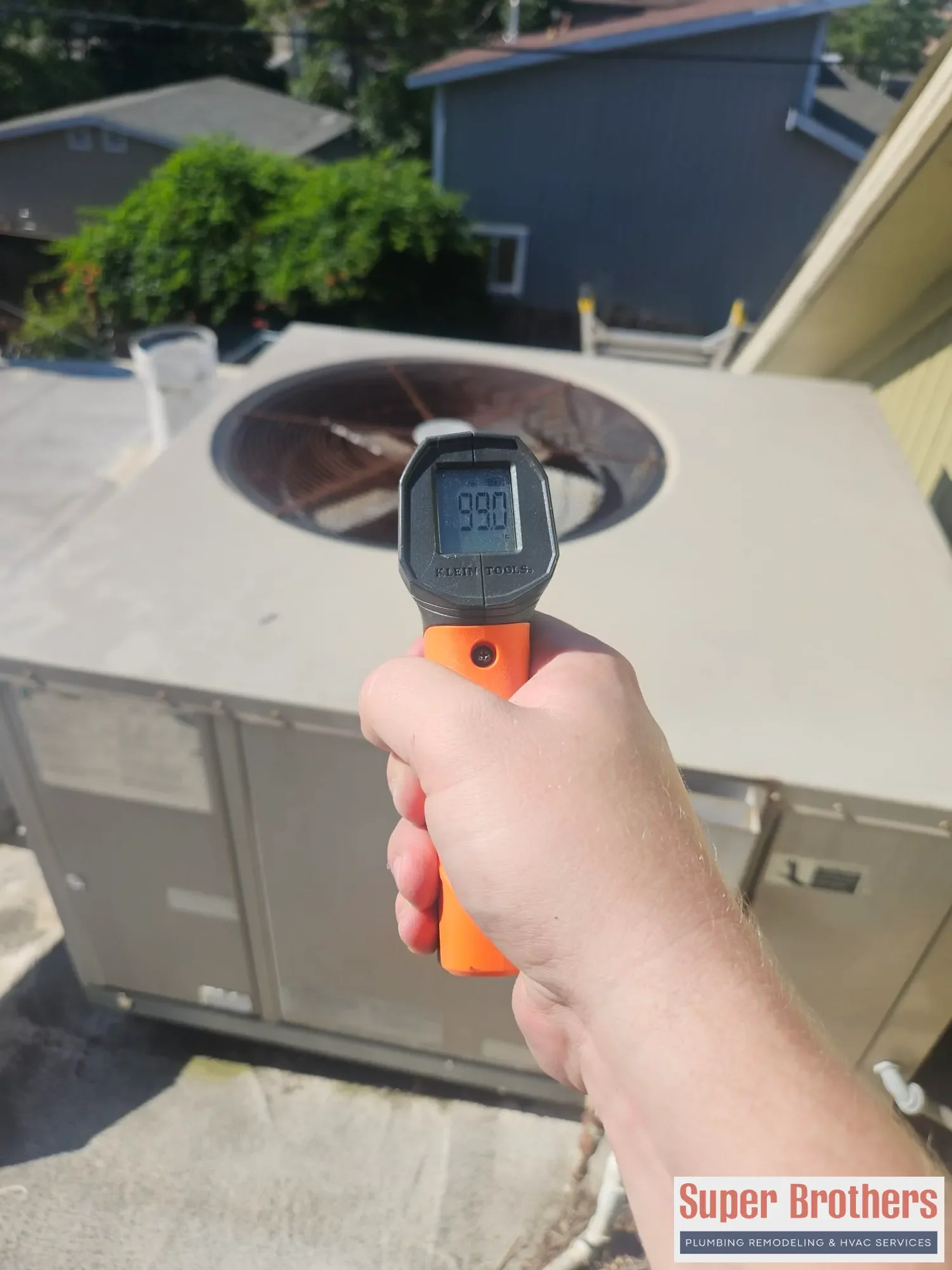 technician checking rooftop AC surface temperature near condenser fan technician checking rooftop AC surface temperature near condenser fan