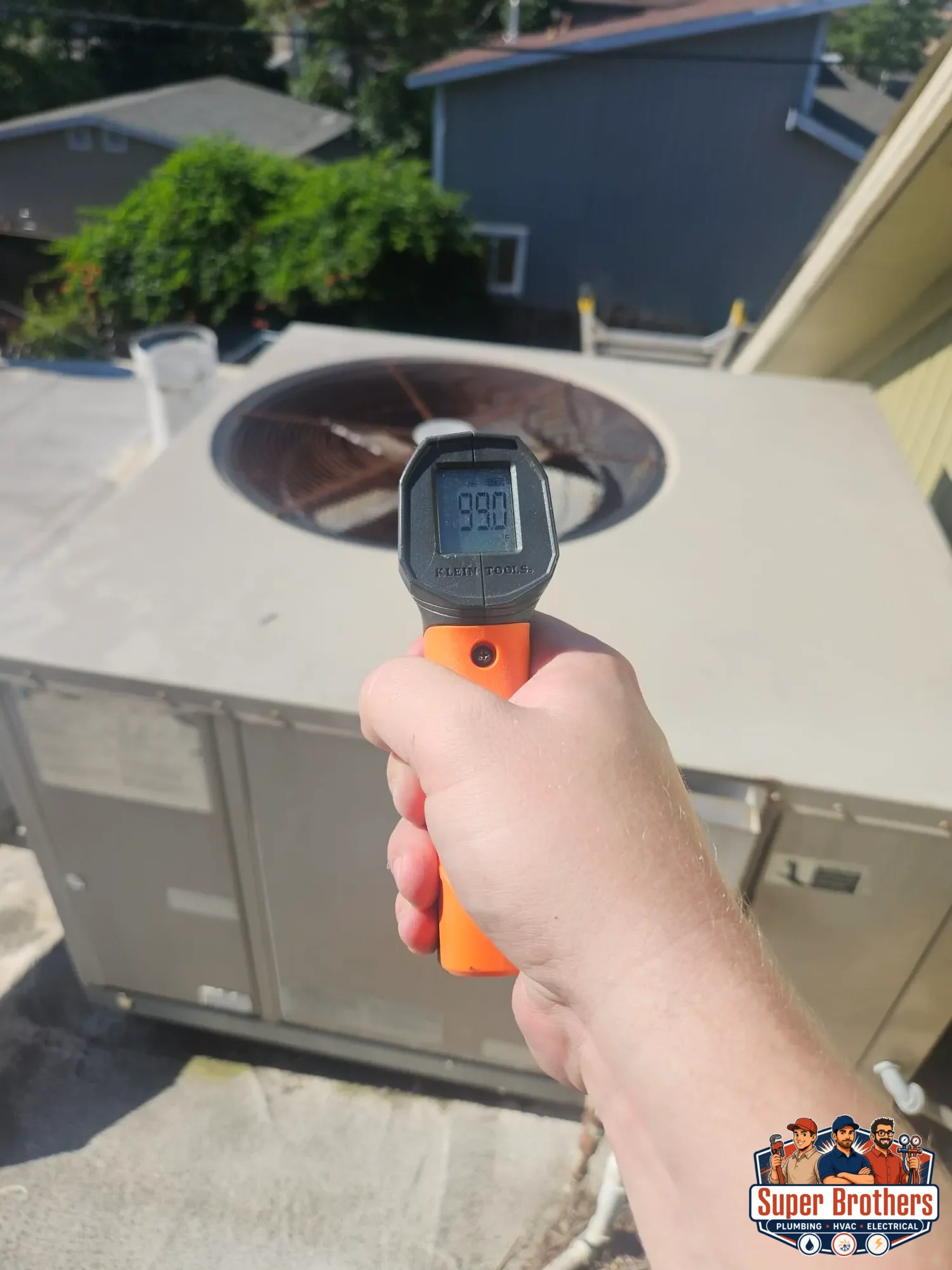 technician checking rooftop AC surface temperature near condenser fan